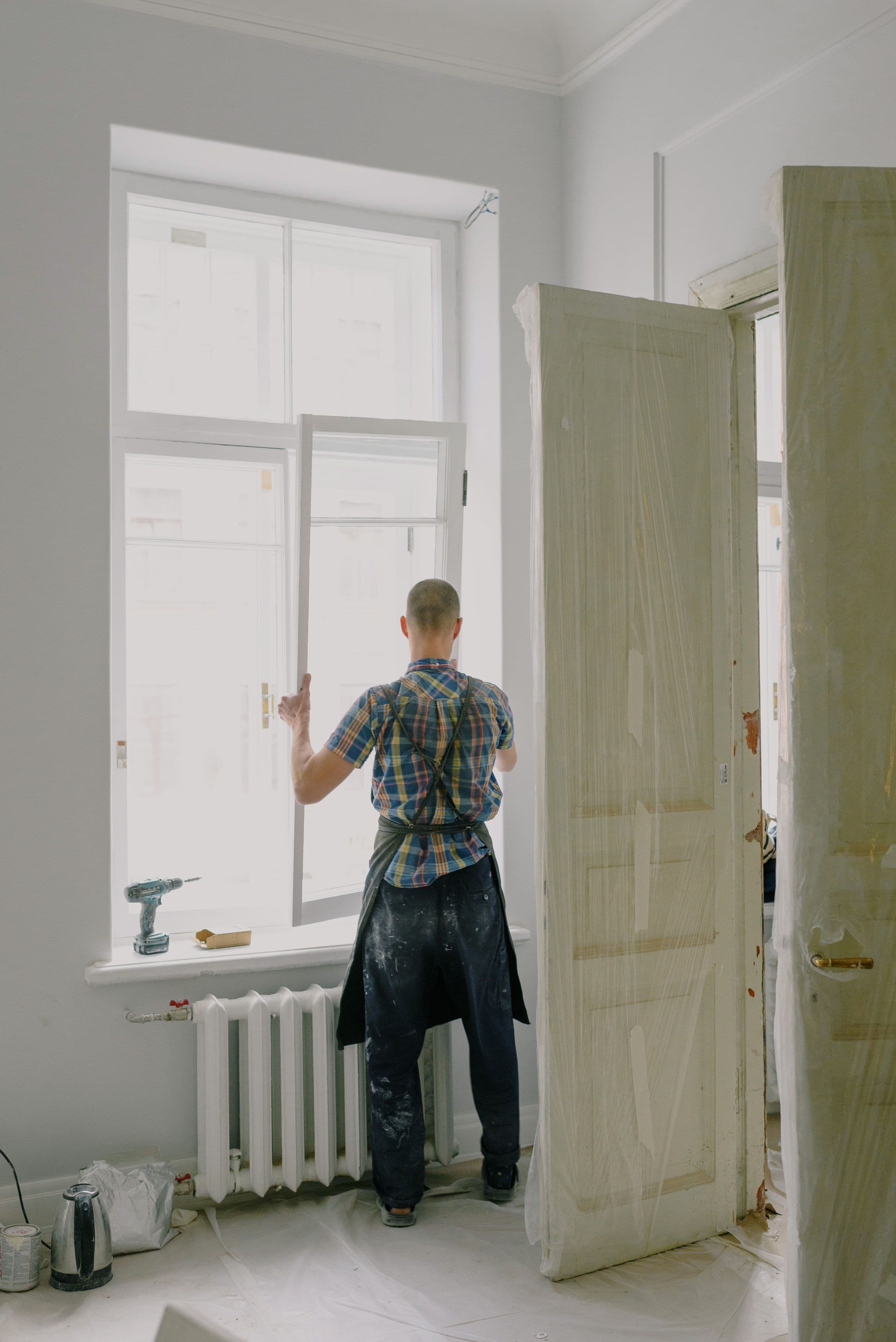 Shengli installer fitting a white window and insect screen inside a room in Tema, Ghana
